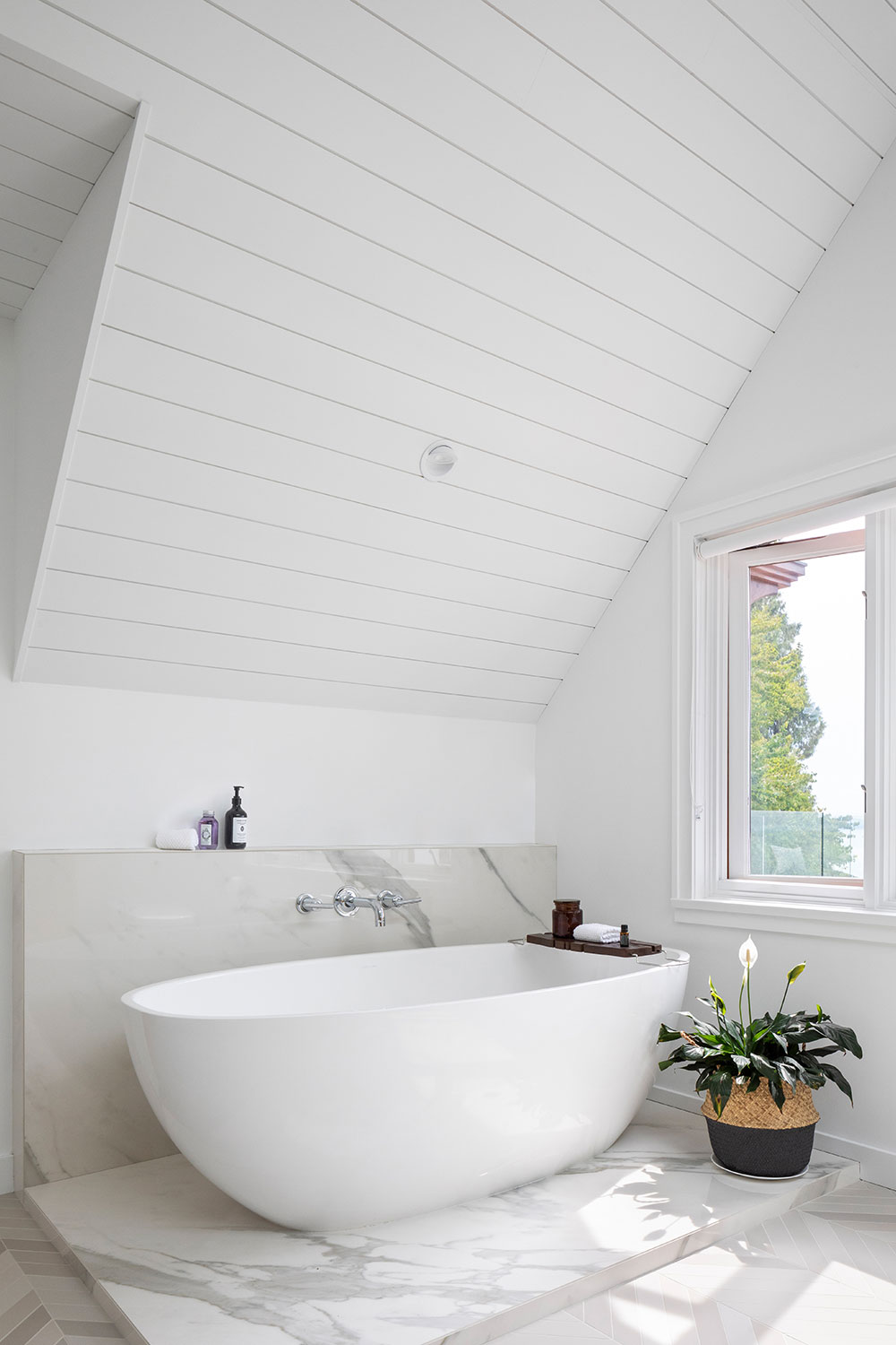 white freestanding soaker tub in renovated upstairs bathroom with angled ceilings