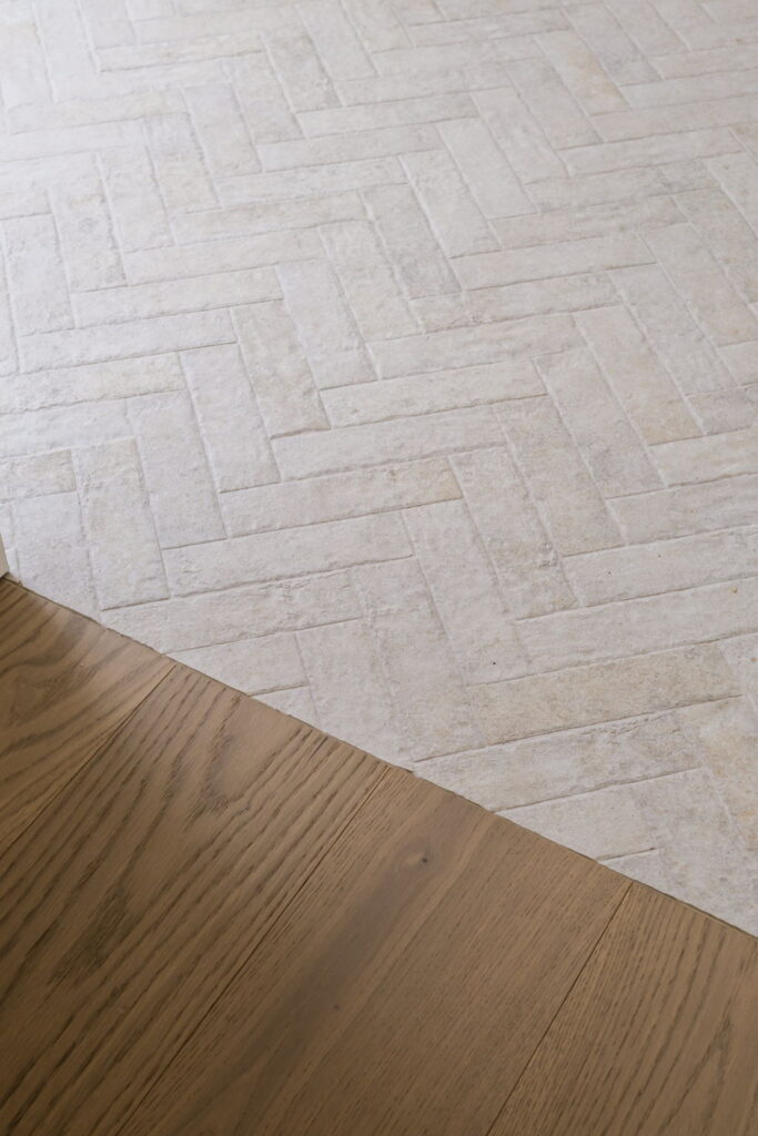 Premium hardwood meeting herringbone tile flooring detail